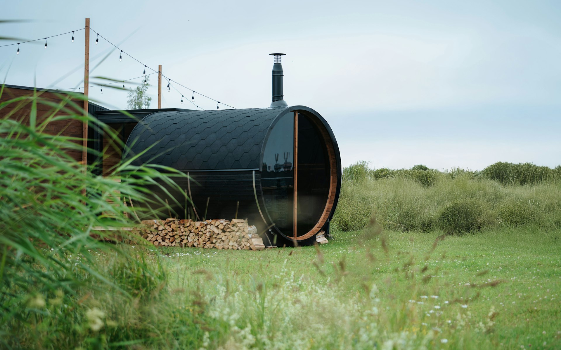 Modern outdoor barrel sauna in a grassy field