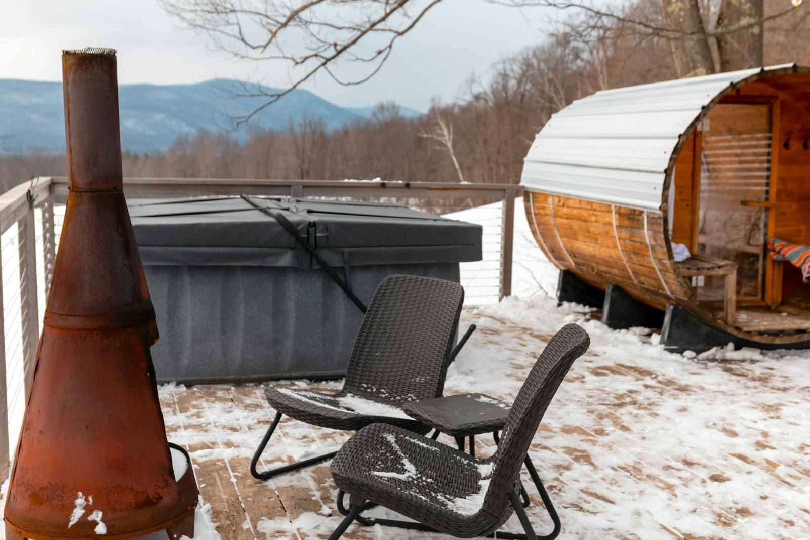 Outdoor wellness retreat deck with barrel sauna, covered plunge tub, and mountain views